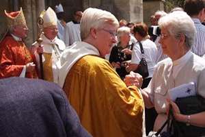 Uma mulher revestida de casula. Ao fundo, Dom Nourrichard, bispo 
de Évreux, ao lado do "bispo" de Salisbury.